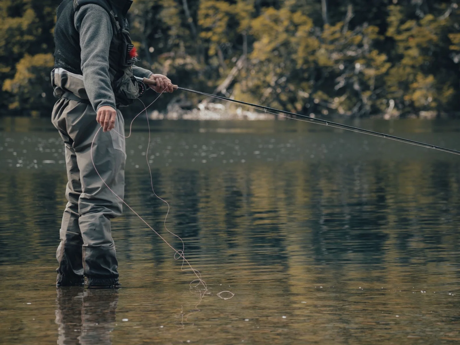 A fly fisherman standing in a calm river