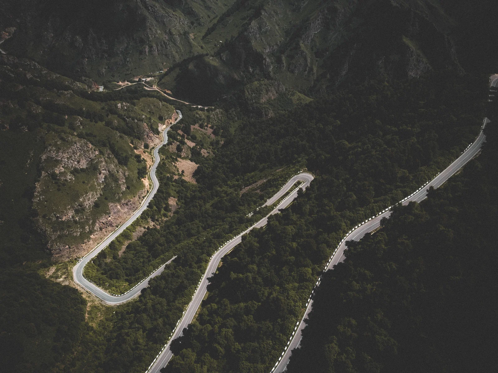 An aerial view of a winding road through forested mountains