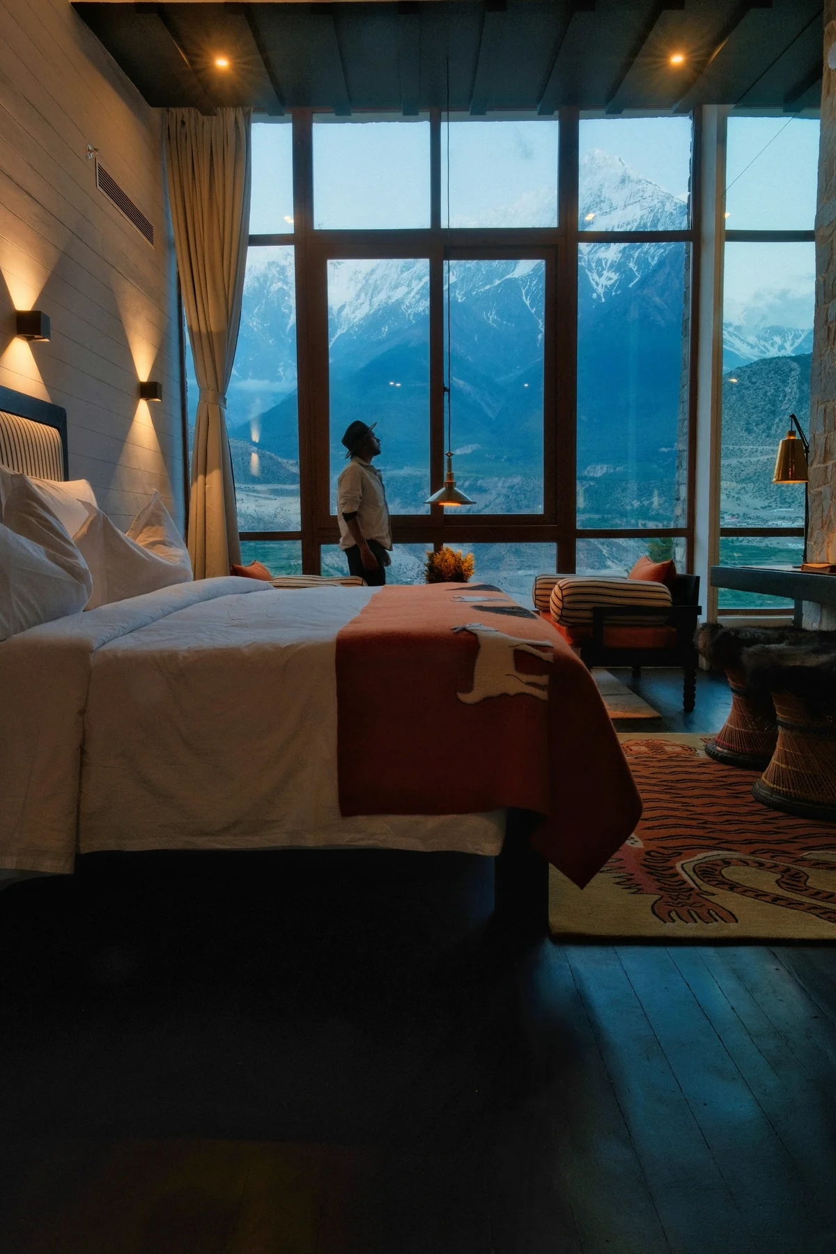A warm timber bedroom with a fireplace, soaking tub, and forest view