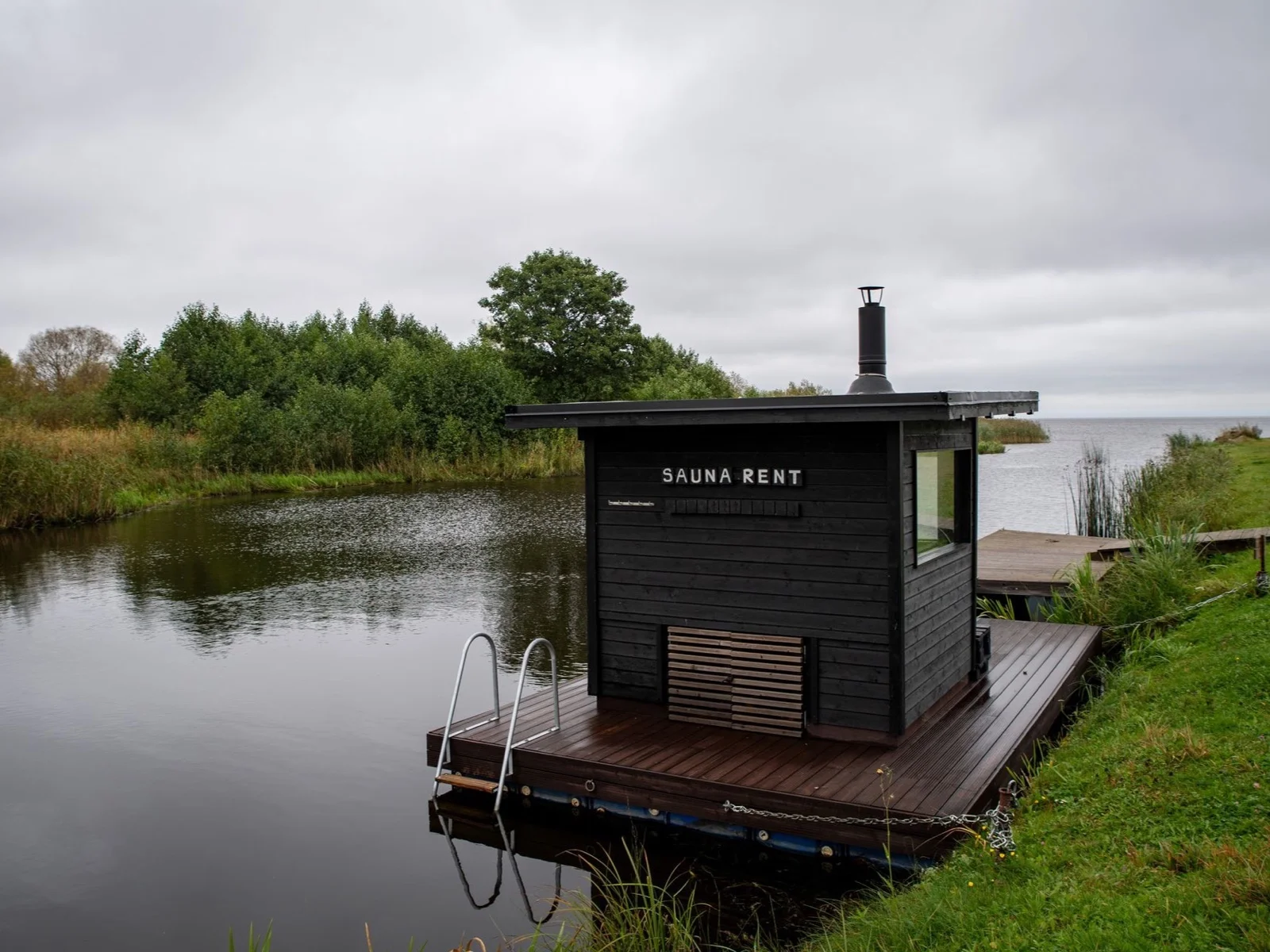 A floating wood-fired sauna beside a tranquil river